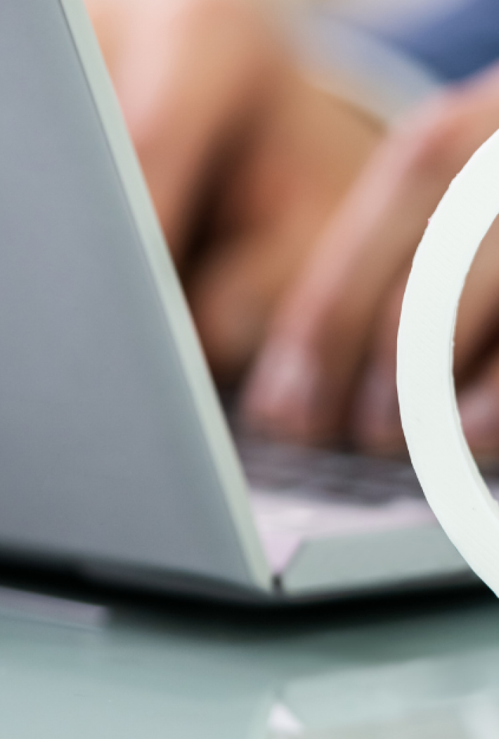 Billedet viser nogle hænder der taster på et laptop keyboard i baggrunden, mens der er et hvidt coyright logo foran